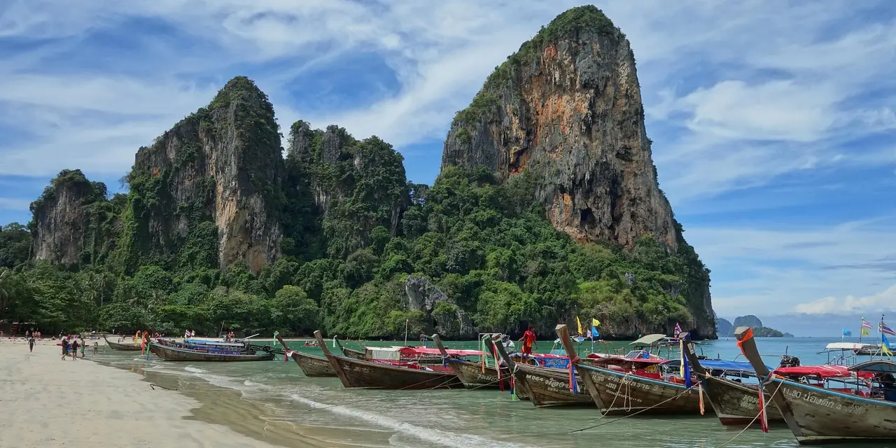 Pirogues à longue queue sur la plage de Railay, au pied des falaises calcaires, en Thaïlande